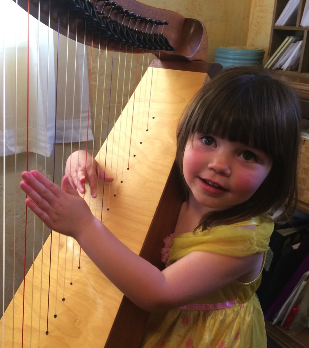 a little girl plays the harp